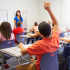 Des élèves dans une classe, l'un d'entre eux lève la main.